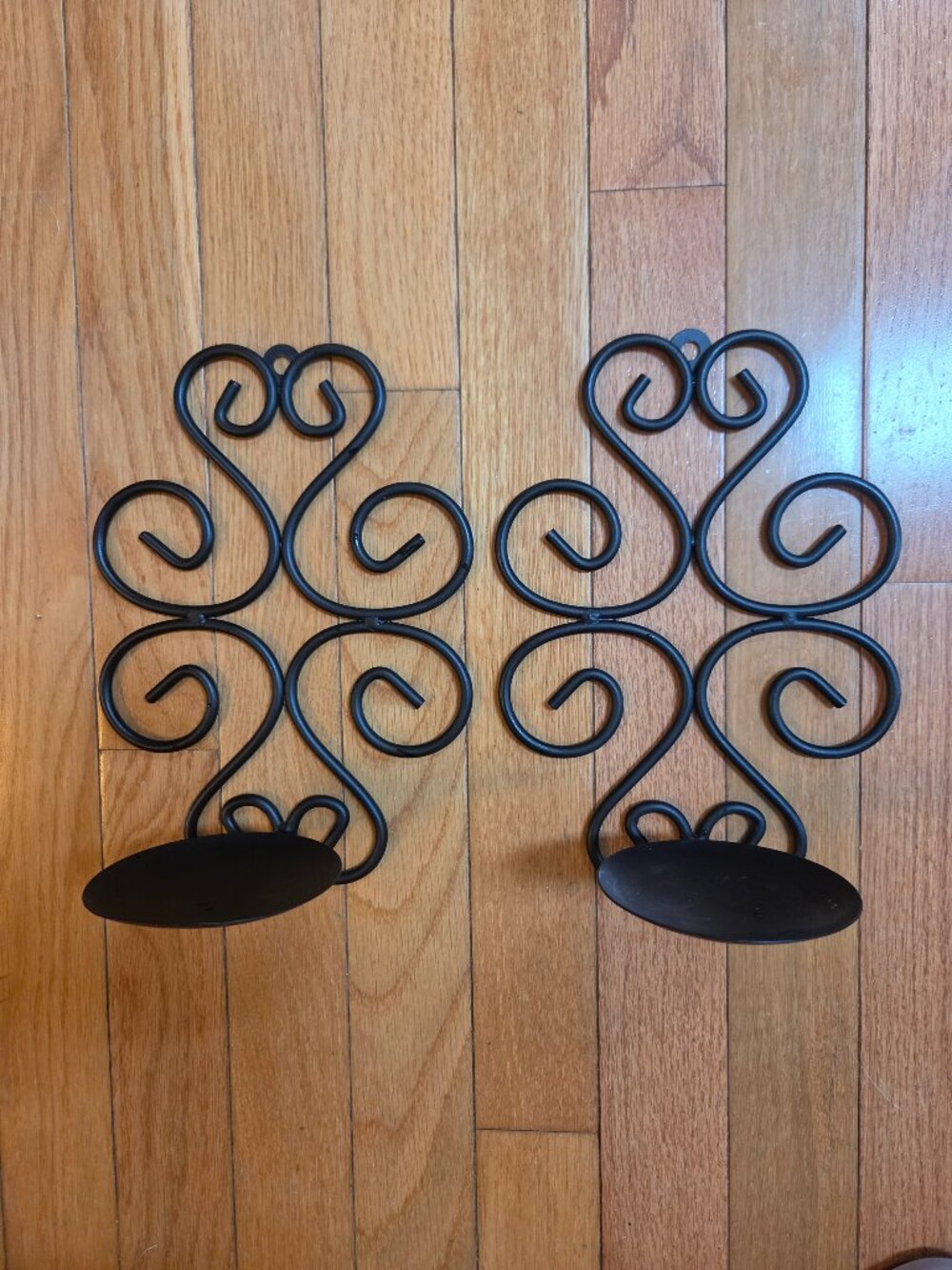 black iron wall sconce with ornate scroll design and round candle plate